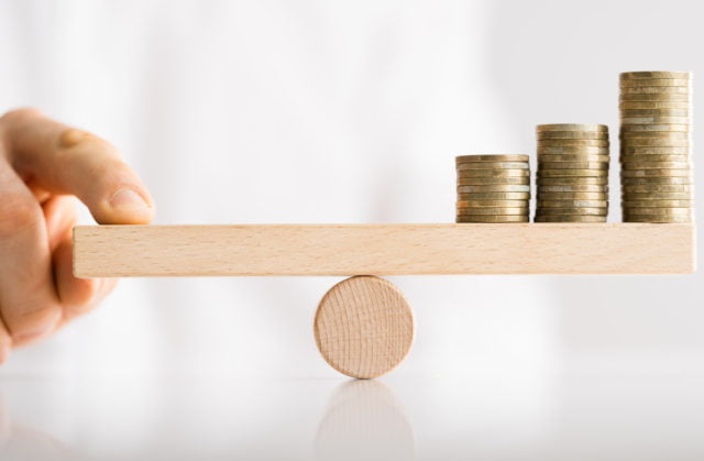 scale with one side coins and the other side a hand