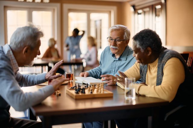 Senior man talking to his friends who are playing chess