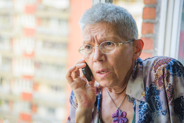 Scared older woman getting news from a cell phone