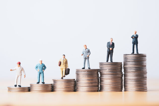 Miniature workers on different height coin stacks