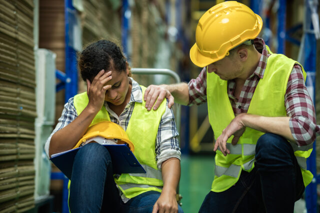 Young African female warehouse worker staff feeling sad and stress while Caucasian man consoling and encouraging due to been fired from job